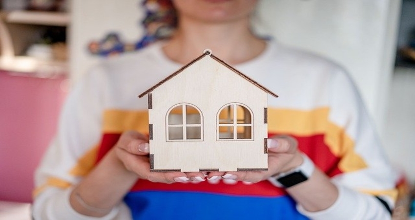 a miniature wooden home in hand